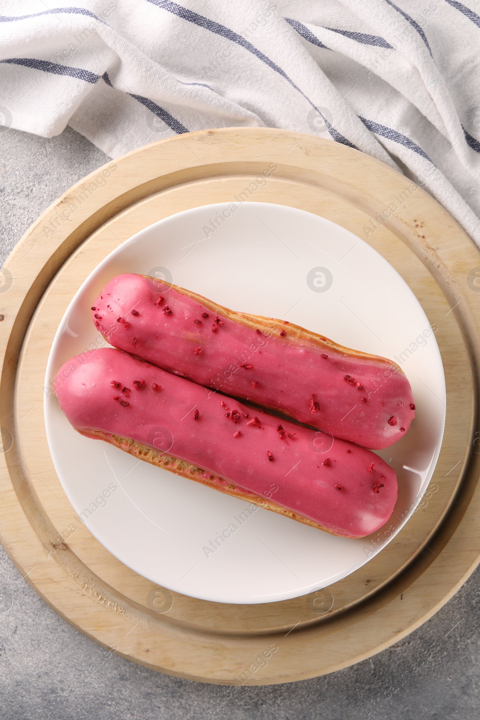 Photo of Plate with tasty glazed eclairs on grey table, top view