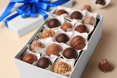 Photo of Box with delicious chocolate candies on beige background, closeup
