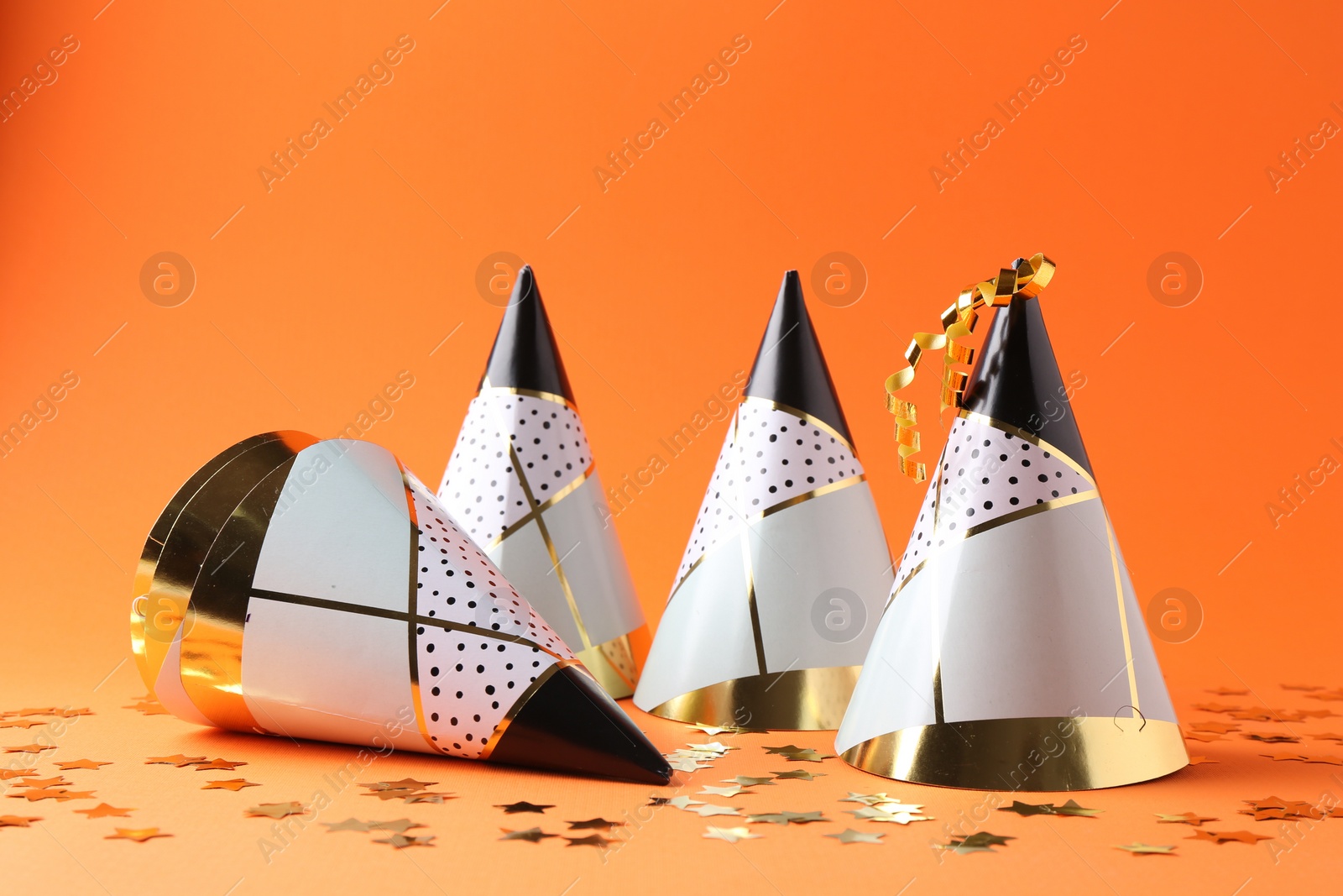 Photo of Party hats and confetti on orange background
