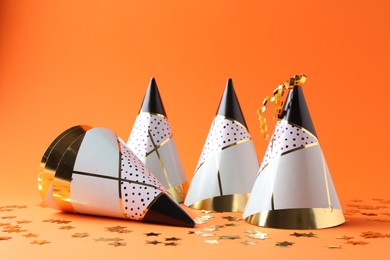 Party hats and confetti on orange background