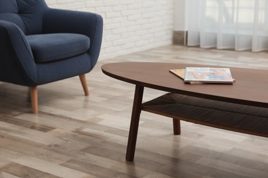 Photo of Magazines on wooden table near armchair indoors