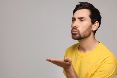 Photo of Handsome man blowing kiss on light grey background. Space for text