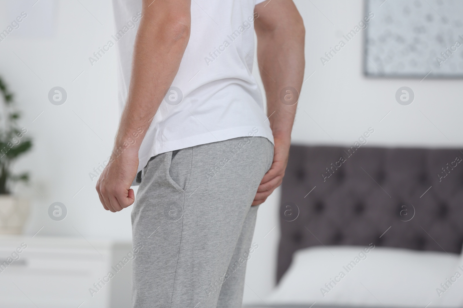 Photo of Man suffering from hemorrhoid in bedroom, closeup