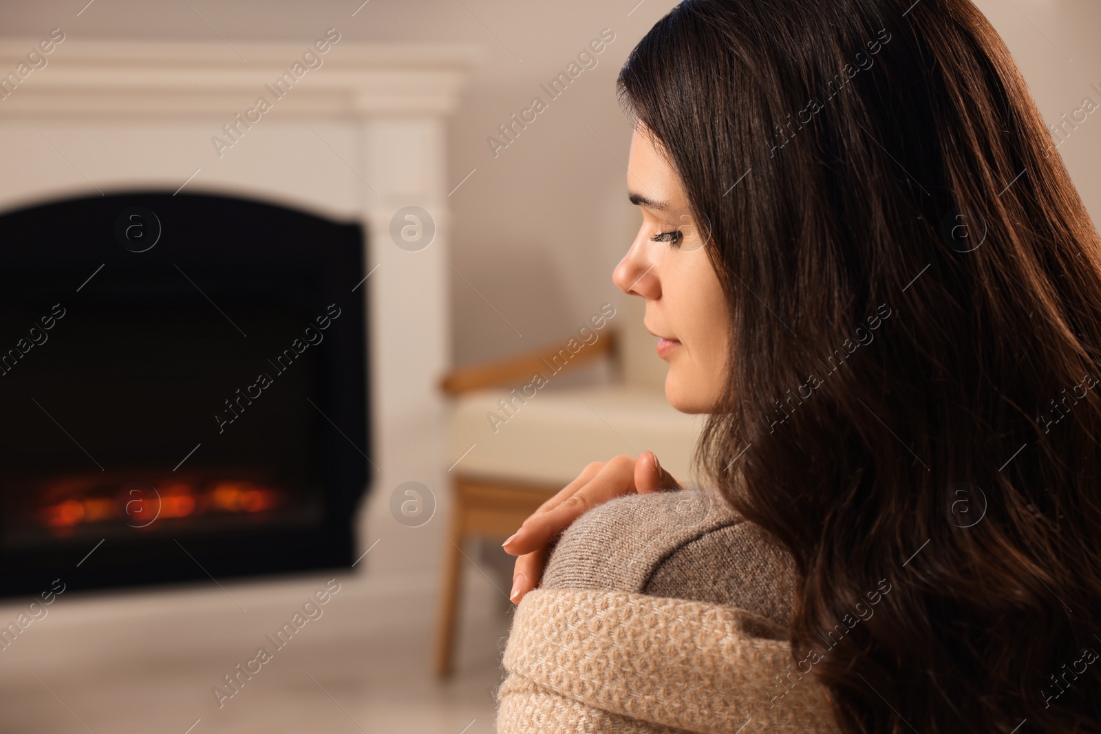 Photo of Young woman relaxing near fireplace at home. Space for text