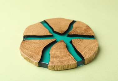 Photo of Stylish wooden cup coaster on pale green background