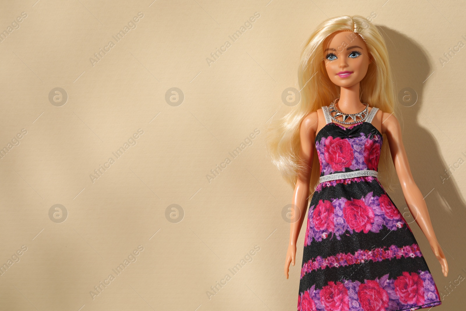 Photo of Mykolaiv, Ukraine - September 4, 2023: Beautiful Barbie doll wearing necklace on beige background, space for text