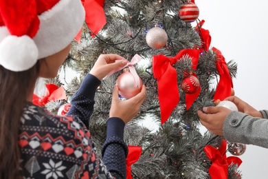 Happy young couple decorating Christmas tree together at home