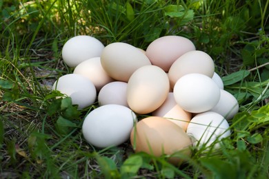 Photo of Pile of fresh raw eggs on green grass outdoors