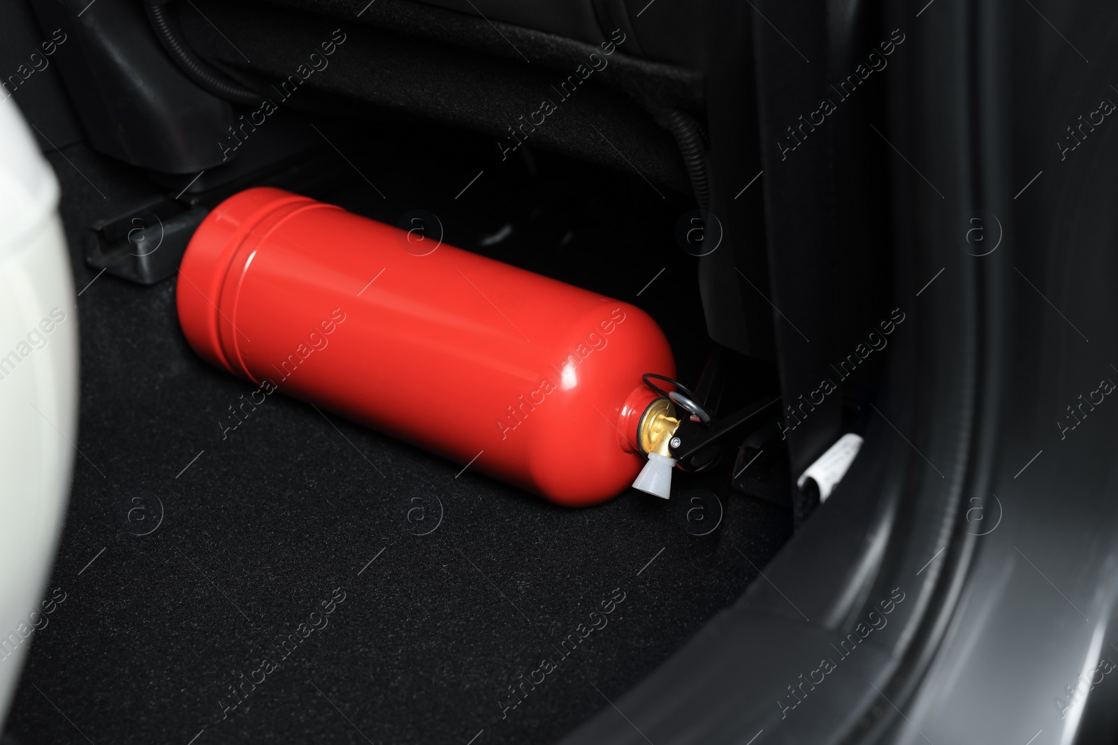 Photo of Red fire extinguisher in trunk. Car safety equipment