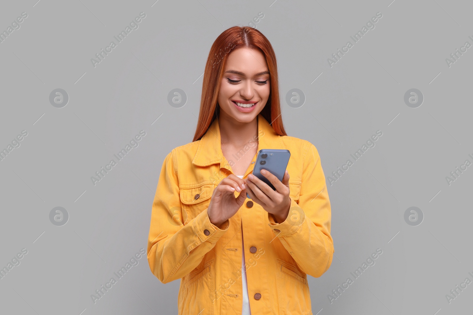 Photo of Beautiful happy woman using smartphone on grey background