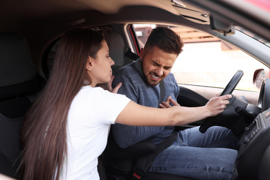 Woman holding steering wheel while driver suffering from heart attack in car