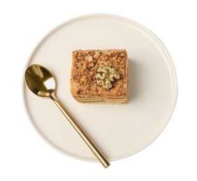 Piece of delicious layered honey cake and spoon on white background, top view