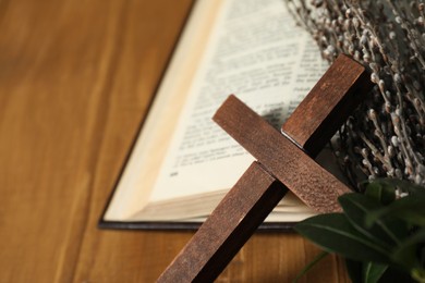 Photo of Cross, Bible and willow branches on table, closeup. Space for text