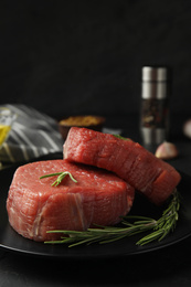 Photo of Fresh raw beef cut with rosemary on table, closeup