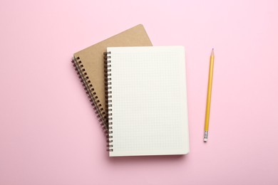 Notebooks and pencil on pink background, top view. Space for text