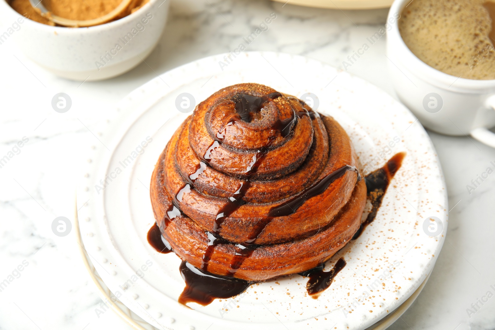 Photo of Plate with freshly baked cinnamon roll on table