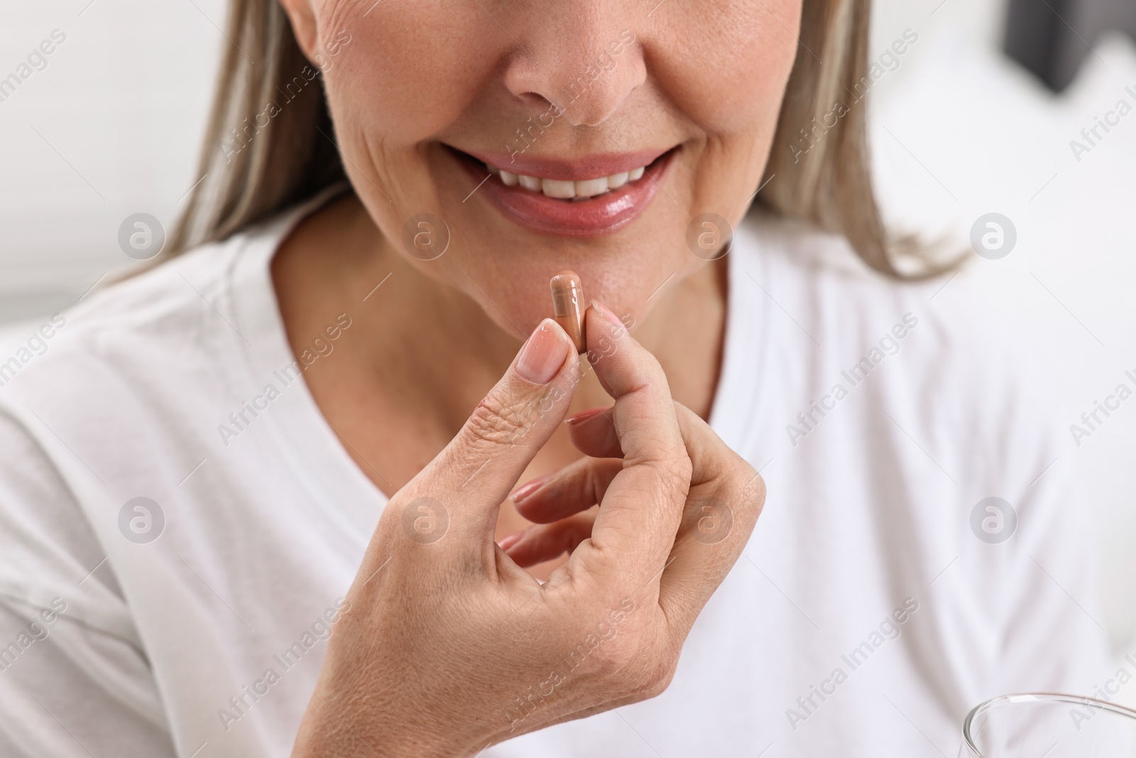 Photo of Woman taking vitamin pill at home, closeup