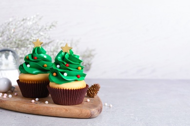 Photo of Christmas tree shaped cupcakes on light grey table. Space for text