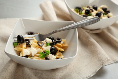 Tasty pasta salad with black olives on table