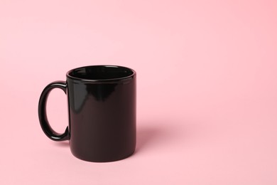 Photo of One black ceramic mug on pink background, space for text