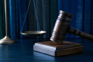 Photo of Wooden gavel, scales of justice and books on table, closeup. Law concept