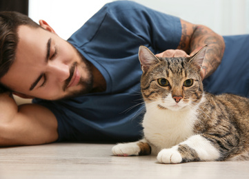 Photo of Man with cat on floor at home. Friendly pet