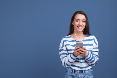 Photo of Young woman using phone for listening to music on color background