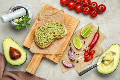 Delicious sandwich with guacamole and ingredients on light grey table, flat lay