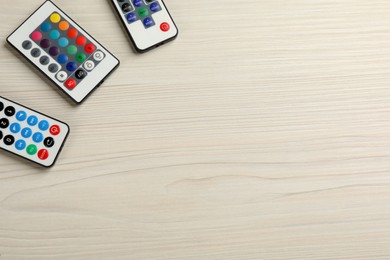 Remote controls on white wooden table, flat lay. Space for text