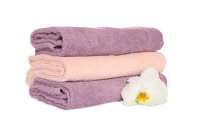 Photo of Stack of clean soft towels with orchid isolated on white