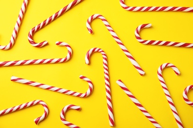 Photo of Flat lay composition with candy canes on yellow background