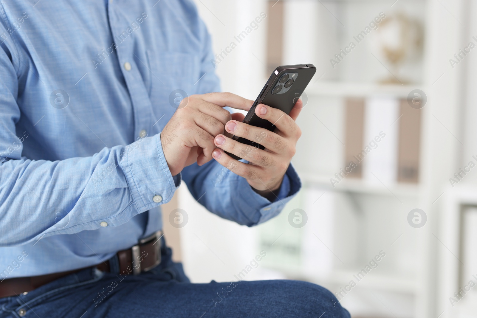 Photo of Man using smartphone in office, closeup view