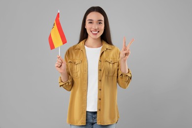 Photo of Young woman holding flag of Spain on light grey background