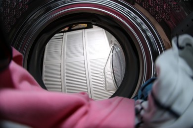 Clothes in washing machine indoors, view from inside. Laundry day