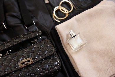 Folded clothes, bracelets, bottle of perfume, bag and black leather jacket , flat lay