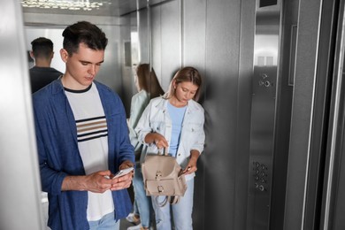 Photo of Young people taking ride in elevator together
