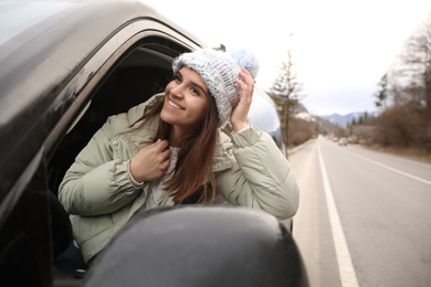Photo of Happy woman leaning out of car window on road. Winter vacation