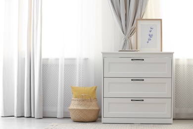 Photo of Chest of drawers near window with stylish curtains in living room. Interior design