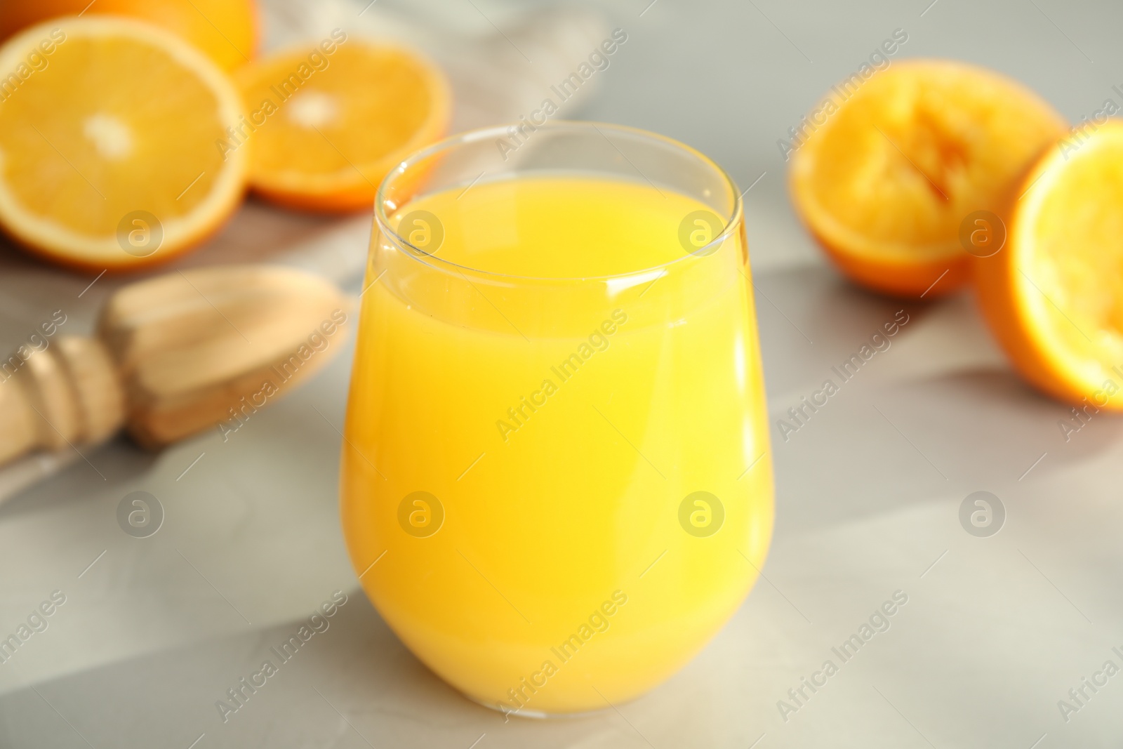 Photo of Freshly made juice, oranges and reamer on table, closeup