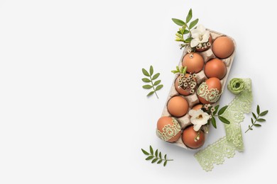 Flat lay composition with Easter eggs, twigs and lace ribbon on white background. Space for text