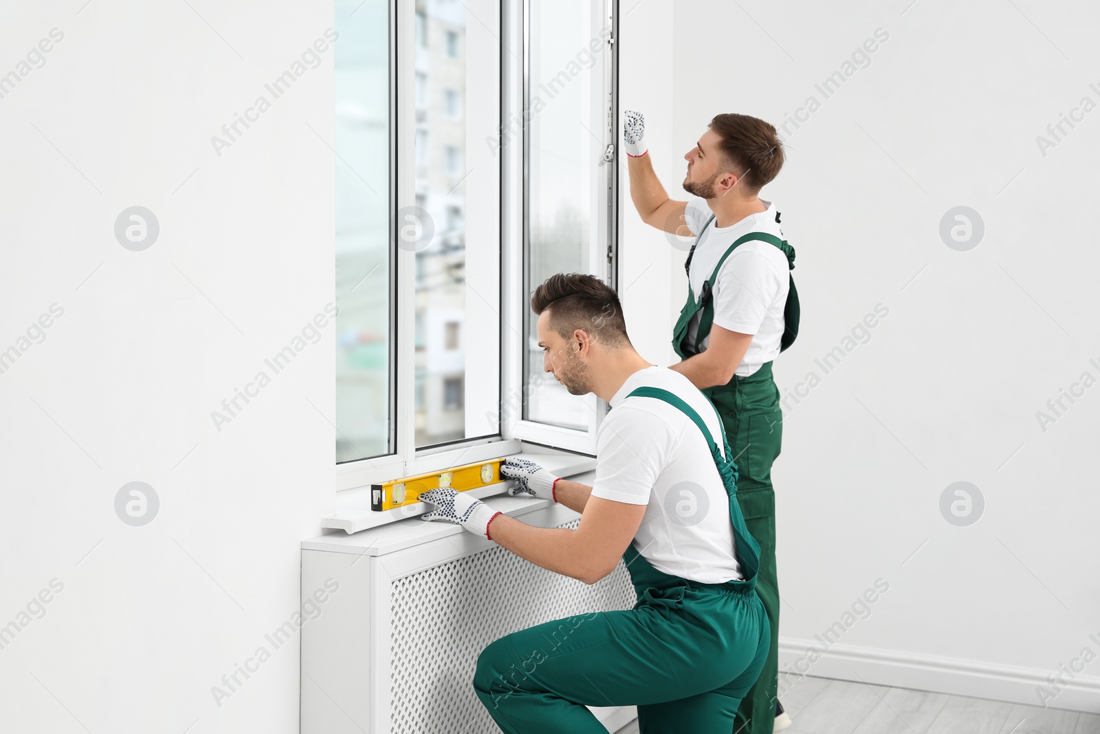 Photo of Construction workers installing plastic window in house