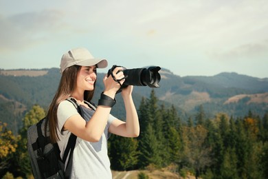 Photo of Professional photographer taking picture with modern camera in mountains