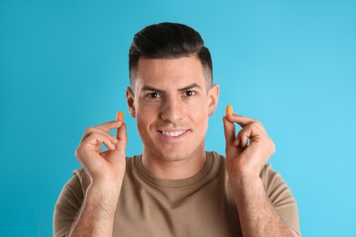 Photo of Man with foam ear plugs on light blue background