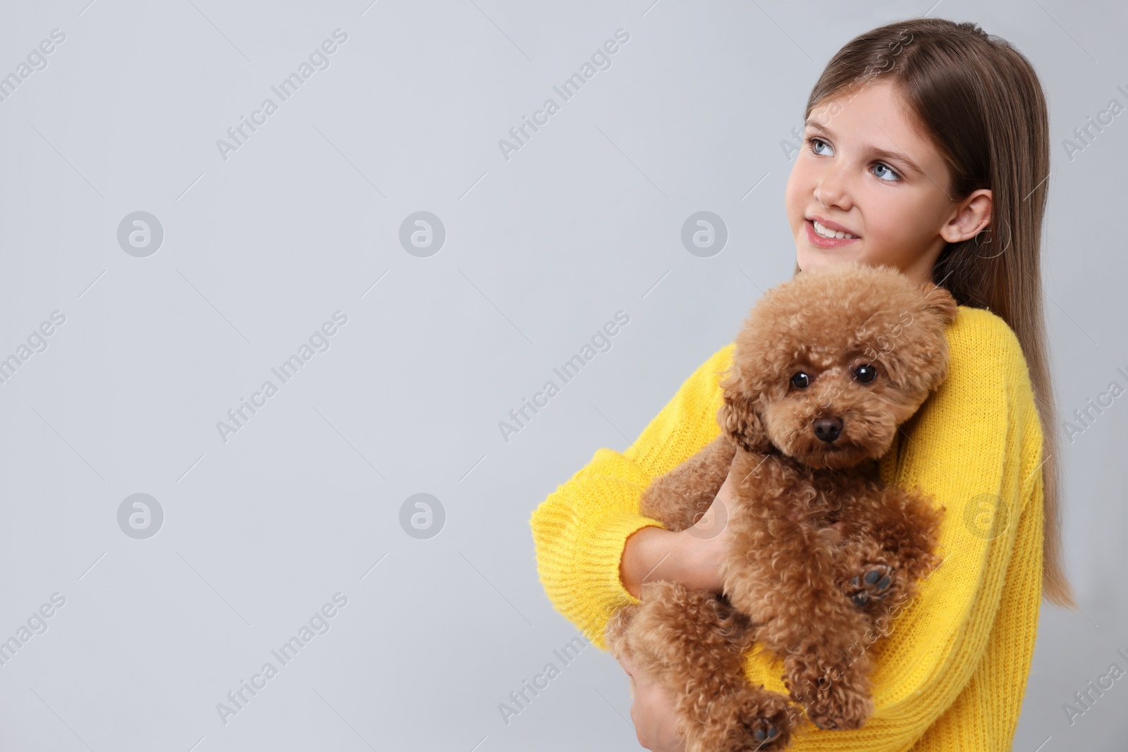 Photo of Little child with cute puppy on light grey background, space for text. Lovely pet