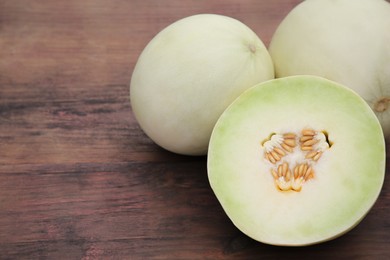 Whole and cut fresh ripe melons on wooden table. Space for text