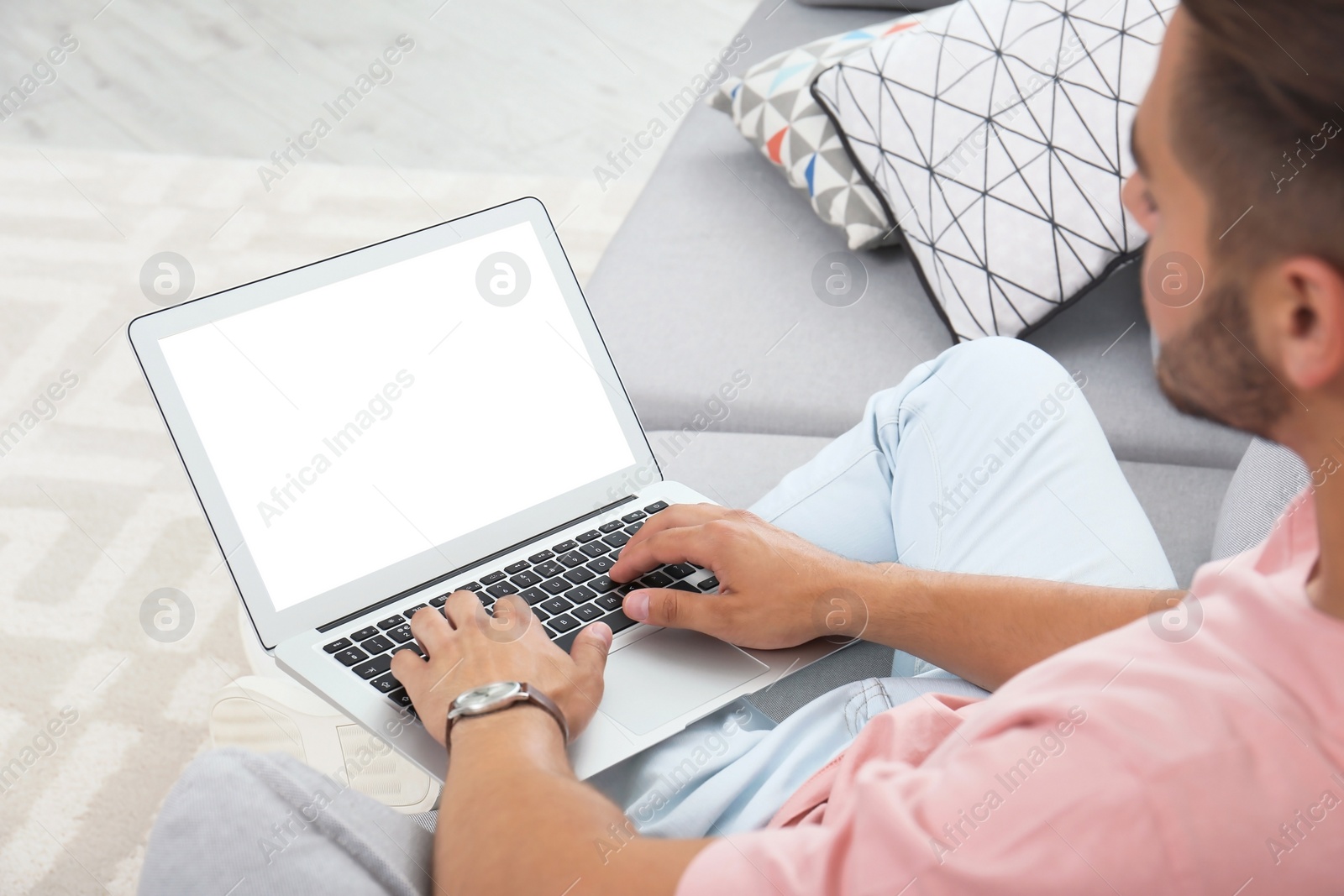 Photo of Man in casual clothes using laptop on sofa at home