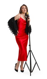 Photo of Beautiful young woman in stylish red dress with microphone singing on white background