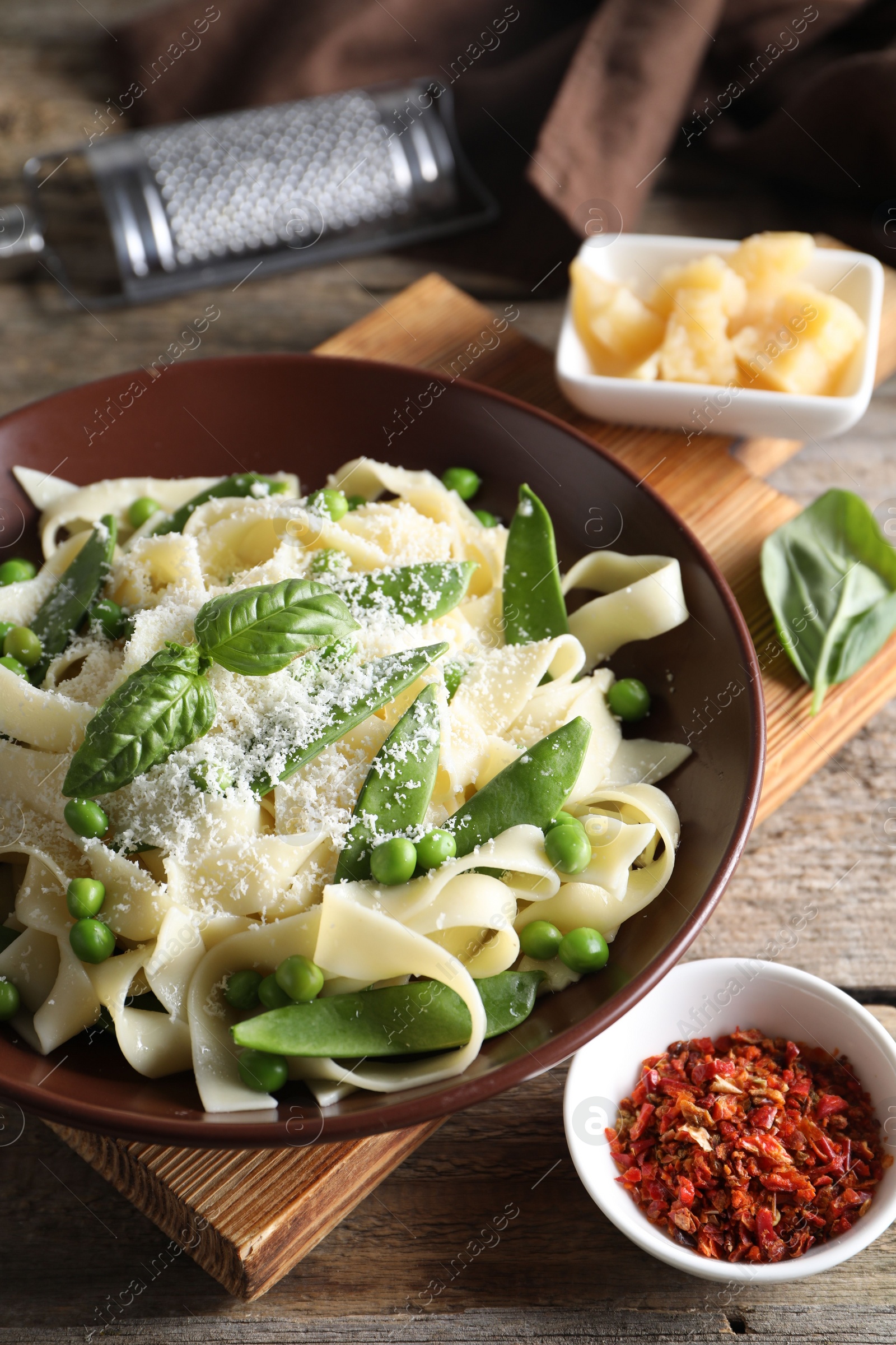 Photo of Delicious pasta with green peas, fresh basil and cheese on wooden table, closeup