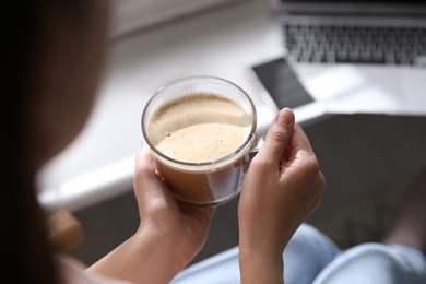 Woman with cup of coffee indoors, closeup