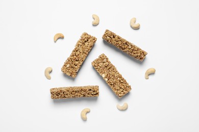 Tasty granola bars and cashew nuts on white background, flat lay